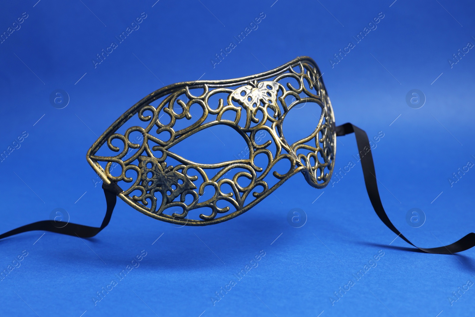 Photo of Beautiful carnival mask in air on blue background