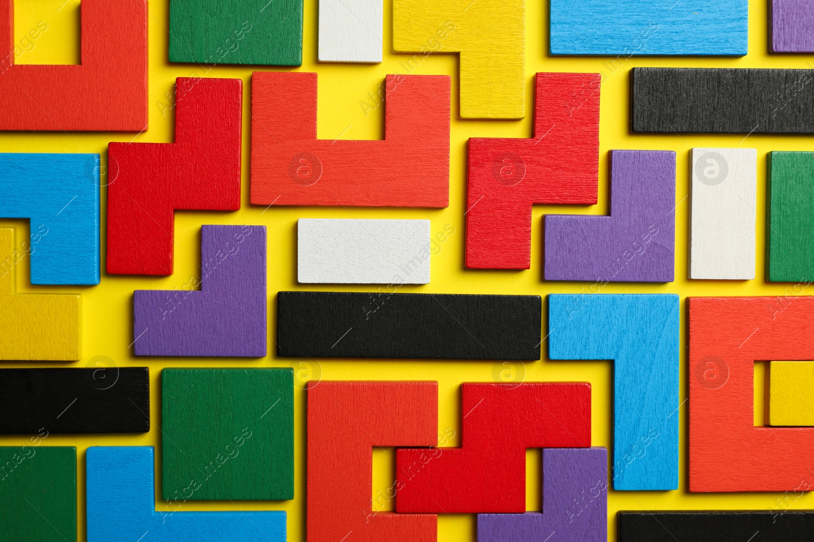 Photo of Colorful wooden puzzle pieces on yellow background, top view