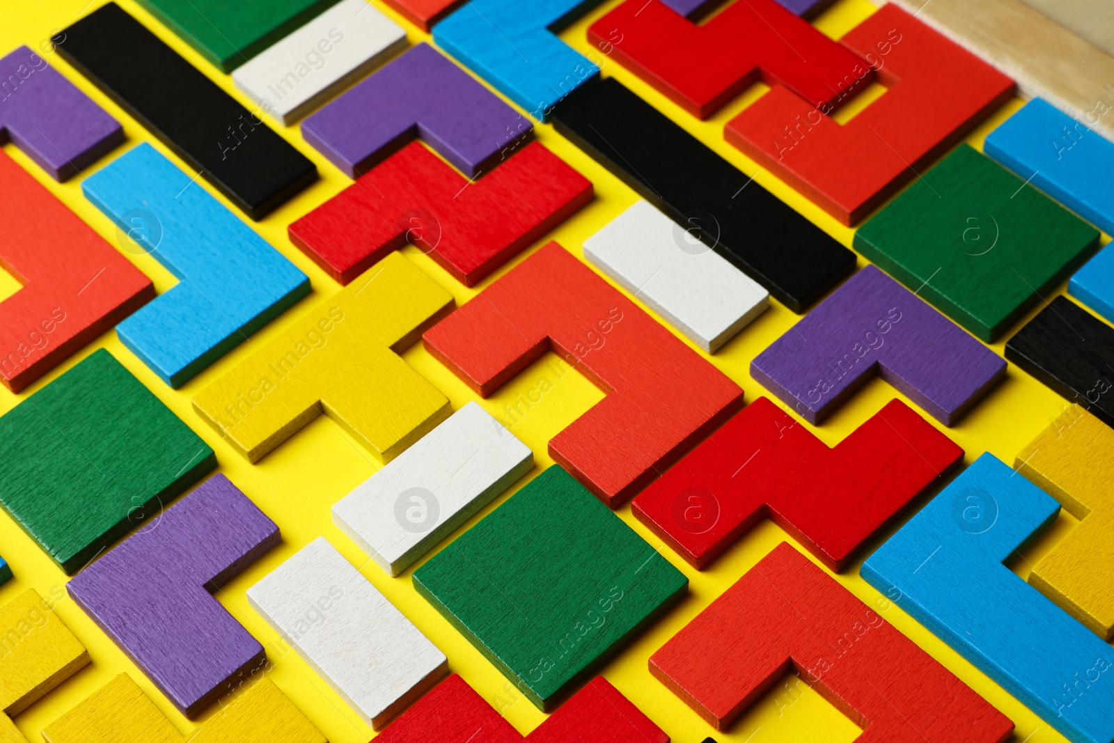 Photo of Colorful wooden puzzle pieces on yellow background, closeup