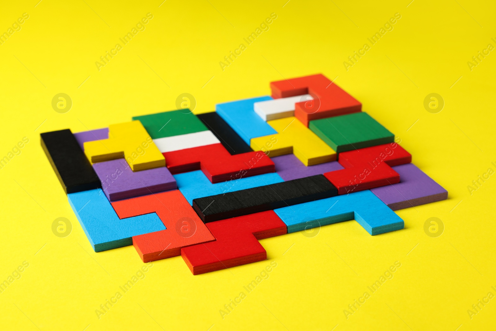 Photo of Colorful wooden puzzle pieces on yellow background, closeup