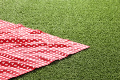 Photo of Checkered picnic tablecloth on green grass. Space for text