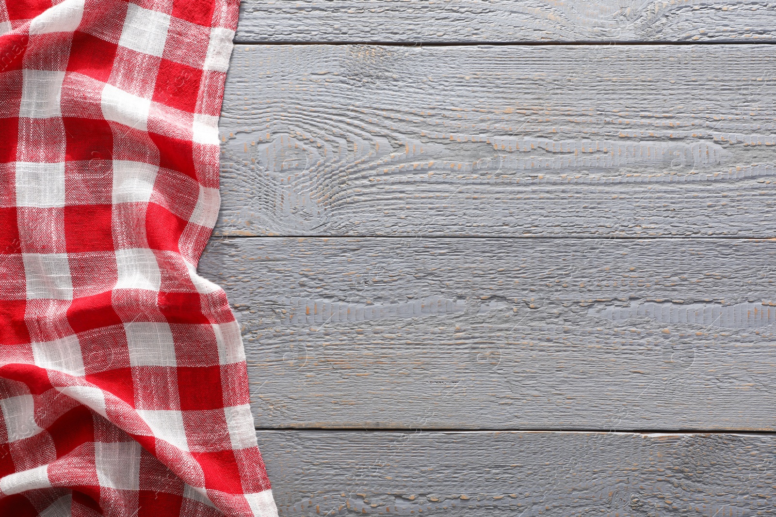 Photo of Red checkered picnic tablecloth on grey wooden table, top view. Space for text