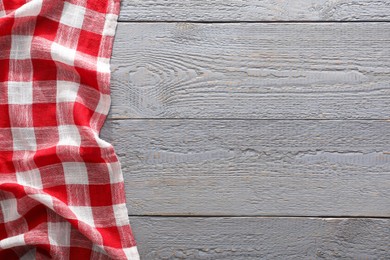 Photo of Red checkered picnic tablecloth on grey wooden table, top view. Space for text