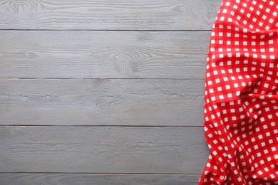 Photo of Red checkered picnic tablecloth on grey wooden table, top view. Space for text