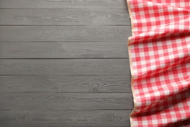 Photo of Red checkered picnic tablecloth on grey wooden table, top view. Space for text