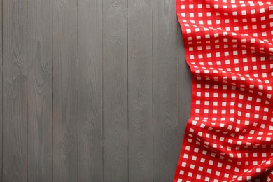 Photo of Red checkered picnic tablecloth on grey wooden table, top view. Space for text