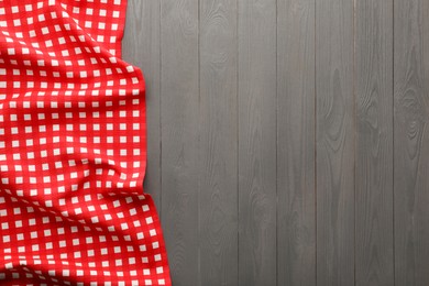 Photo of Red checkered picnic tablecloth on grey wooden table, top view. Space for text