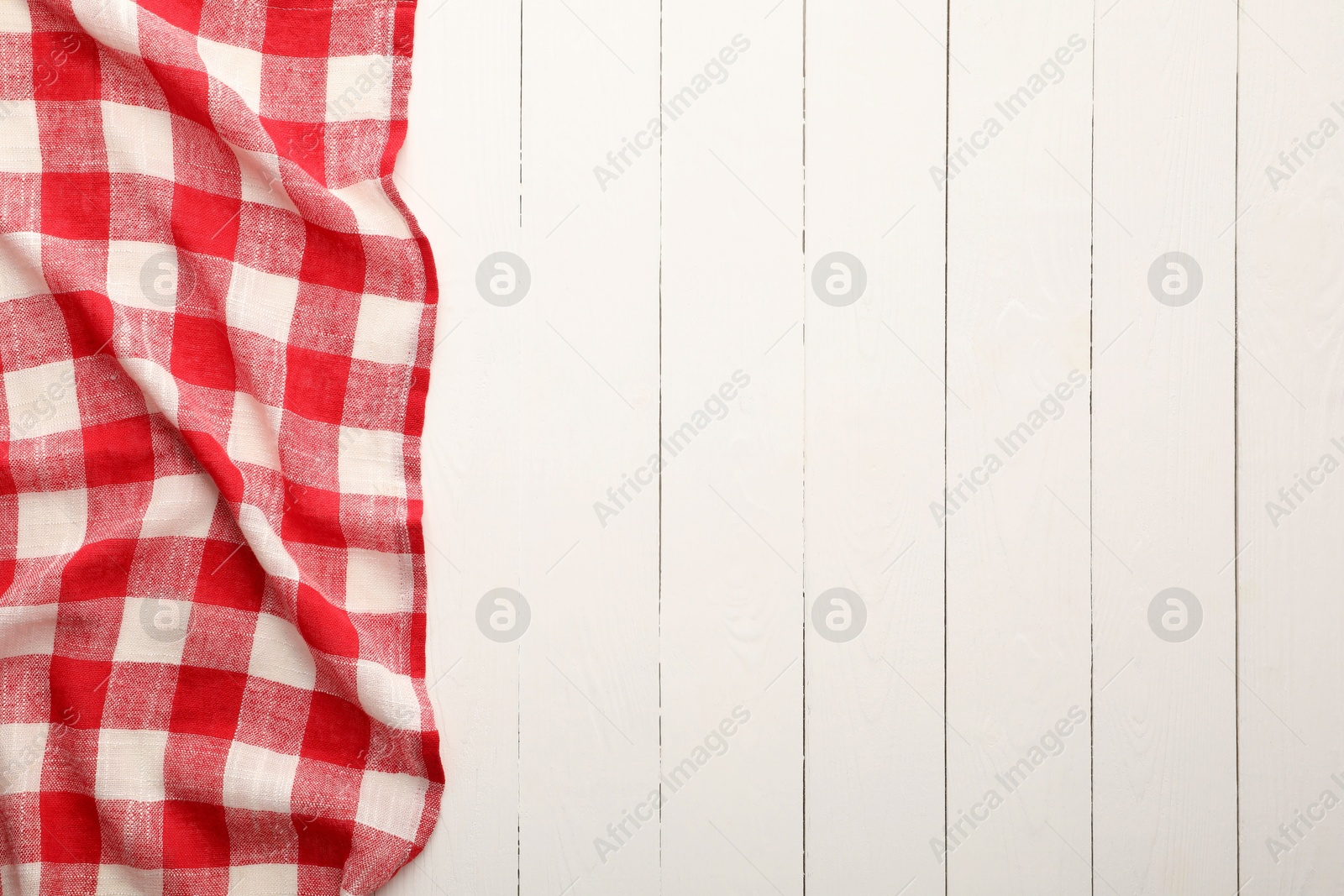 Photo of Red checkered picnic tablecloth on white wooden table, top view. Space for text