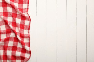 Red checkered picnic tablecloth on white wooden table, top view. Space for text