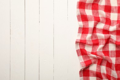 Photo of Red checkered picnic tablecloth on white wooden table, top view. Space for text