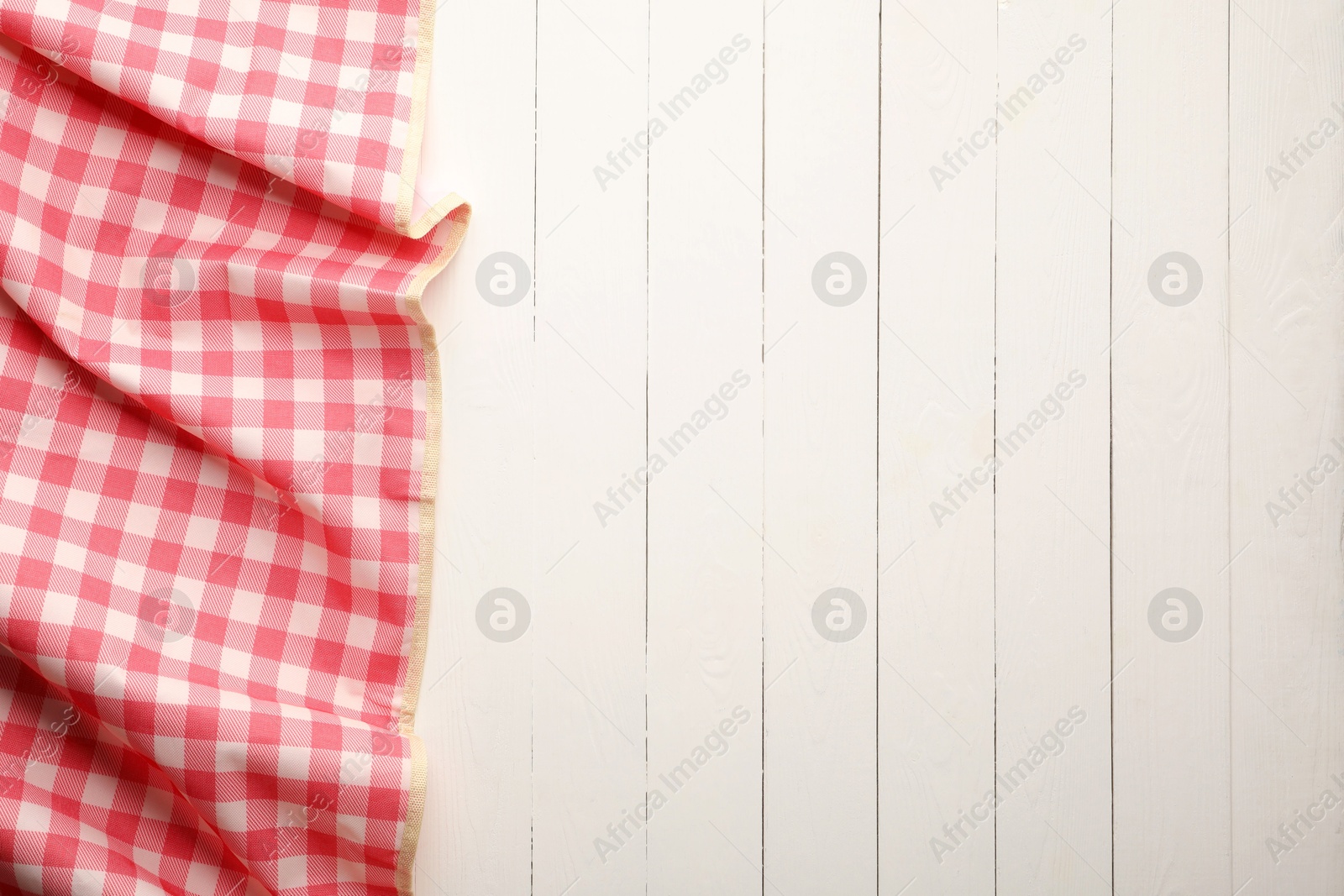 Photo of Red checkered picnic tablecloth on white wooden table, top view. Space for text