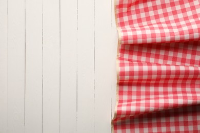 Red checkered picnic tablecloth on white wooden table, top view. Space for text