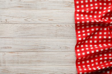 Photo of Red checkered picnic tablecloth on wooden table, top view. Space for text