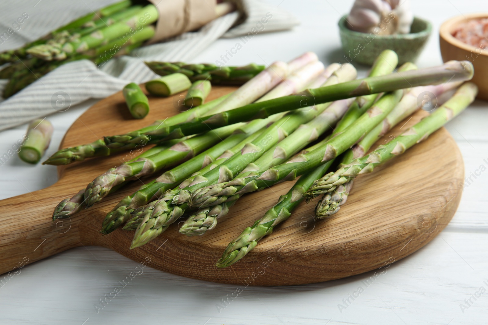 Photo of Fresh green asparagus stems on white wooden table, closeup