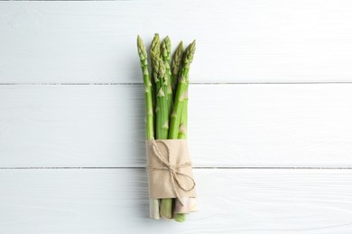 Bunch of fresh green asparagus stems on white wooden table, top view