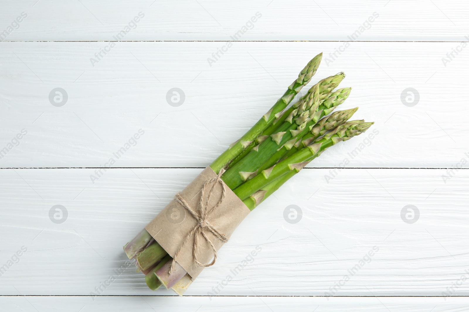 Photo of Bunch of fresh green asparagus stems on white wooden table, top view