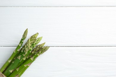 Fresh green asparagus stems on white wooden table, top view. Space for text