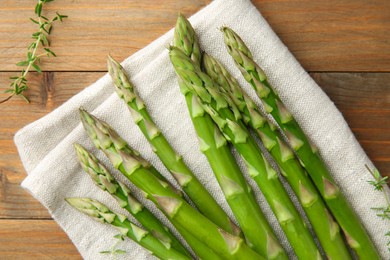 Fresh green asparagus stems and thyme on wooden table, top view