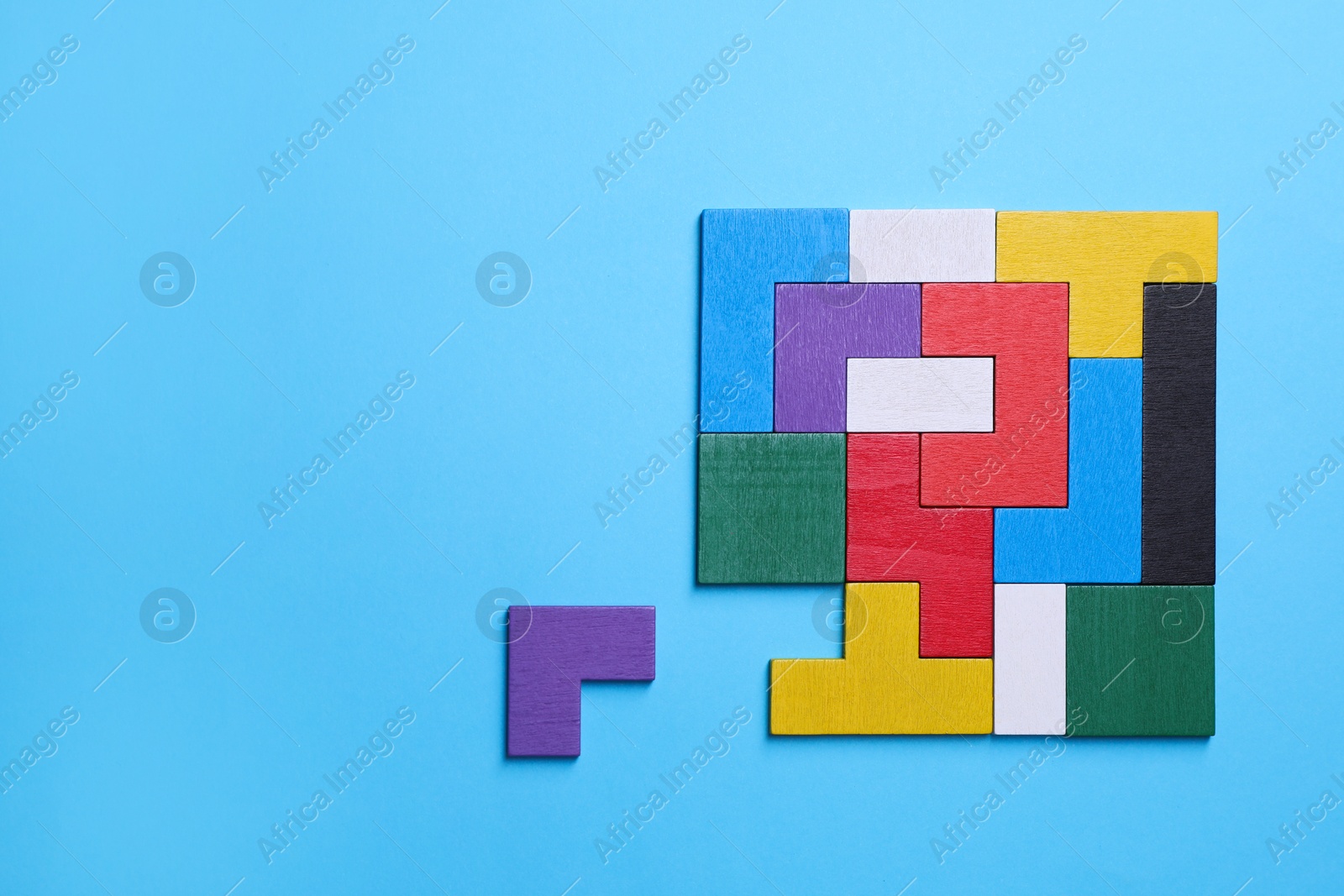 Photo of Colorful wooden puzzle pieces on light blue background, top view. Space for text