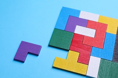 Photo of Colorful wooden puzzle pieces on light blue background, closeup