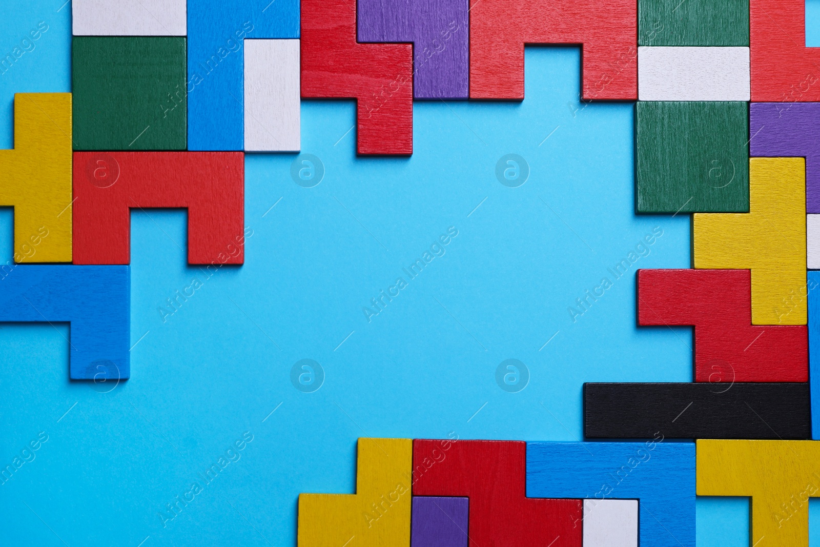 Photo of Colorful wooden puzzle pieces on light blue background, top view. Space for text