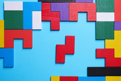 Photo of Colorful wooden puzzle pieces on light blue background, top view