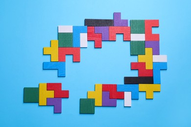 Colorful wooden puzzle pieces on light blue background, top view