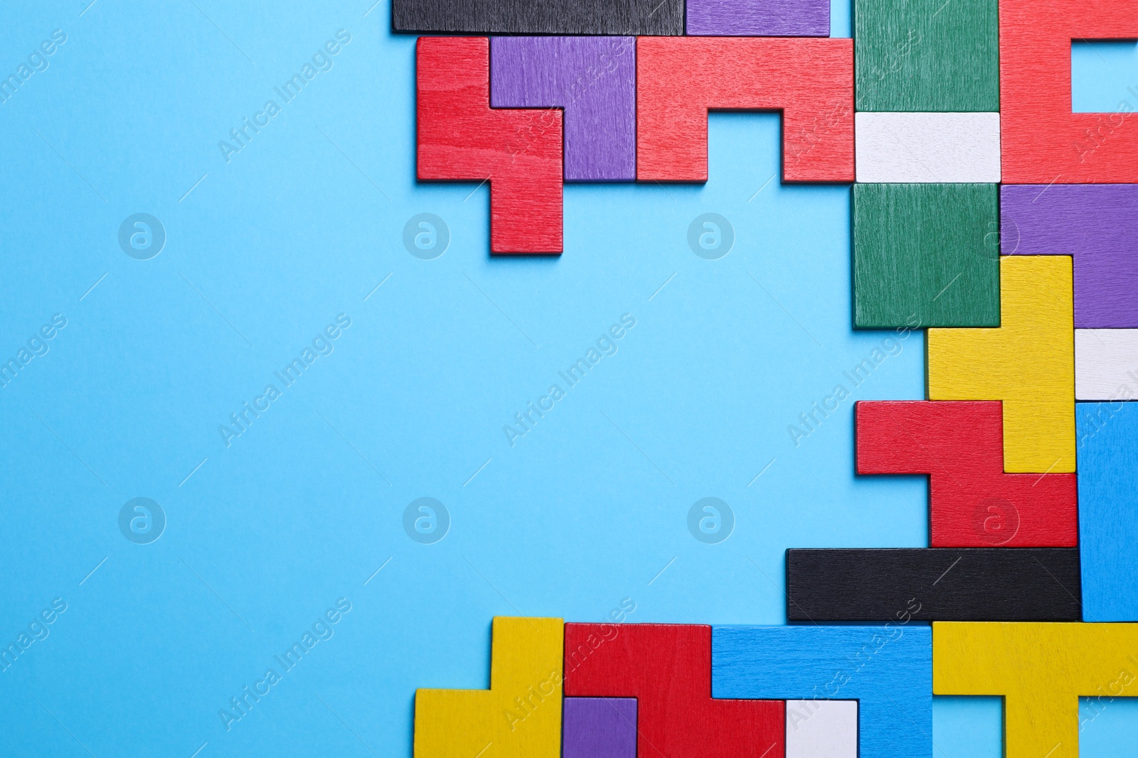 Photo of Colorful wooden puzzle pieces on light blue background, top view. Space for text