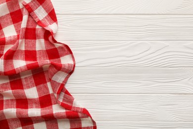 Photo of Red checkered picnic tablecloth on white wooden table, top view. Space for text