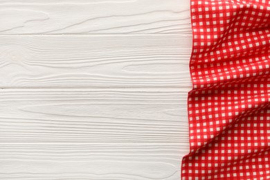 Photo of Red checkered picnic tablecloth on white wooden table, top view. Space for text