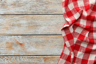 Photo of Red checkered picnic tablecloth on old wooden table, top view. Space for text