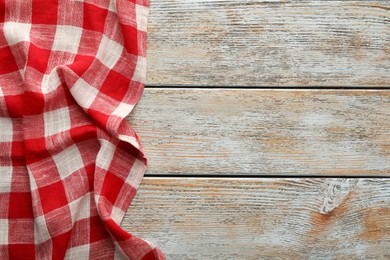 Photo of Red checkered picnic tablecloth on old wooden table, top view. Space for text