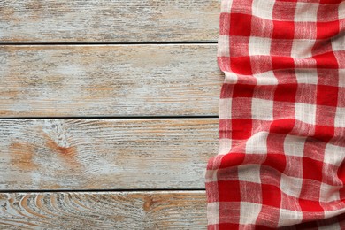 Photo of Red checkered picnic tablecloth on old wooden table, top view. Space for text