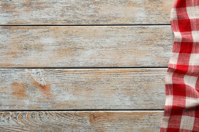 Photo of Red checkered picnic tablecloth on old wooden table, top view. Space for text