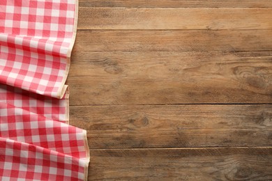 Photo of Red checkered picnic tablecloth on wooden table, top view. Space for text