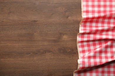 Photo of Red checkered picnic tablecloth on wooden table, top view. Space for text