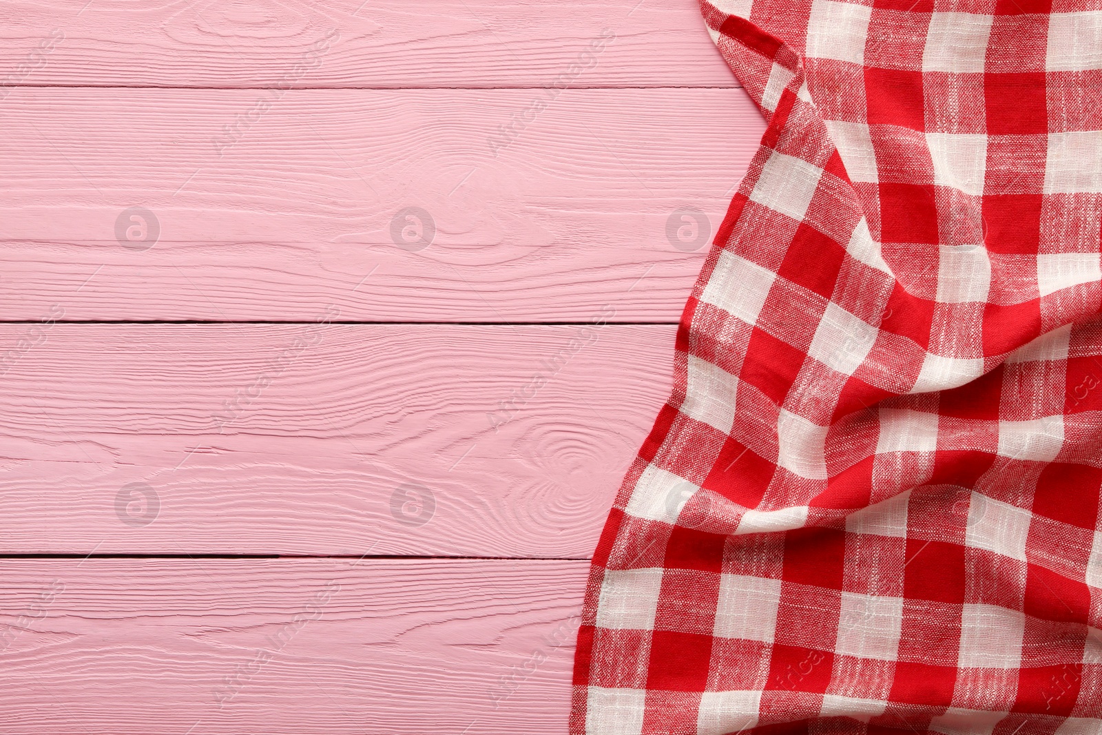 Red checkered picnic tablecloth on pink wooden table, top view. Space for text Photo of Red checkered picnic tablecloth on pink wooden table, top view. Space for text