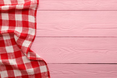 Red checkered picnic tablecloth on pink wooden table, top view. Space for text