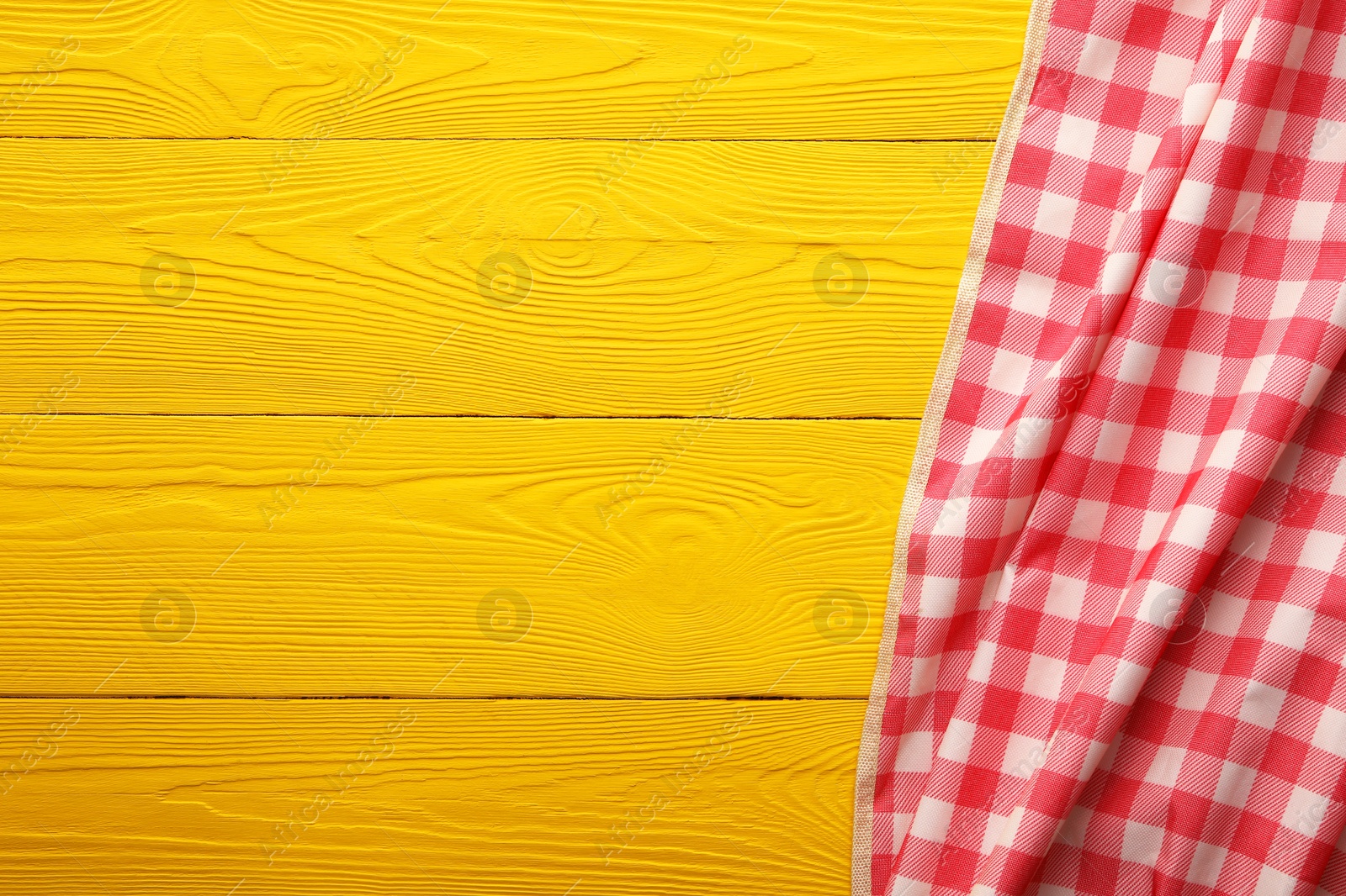 Red checkered picnic tablecloth on yellow wooden table, top view. Space for text Photo of Red checkered picnic tablecloth on yellow wooden table, top view. Space for text
