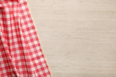 Photo of Red checkered picnic tablecloth on wooden table, top view. Space for text