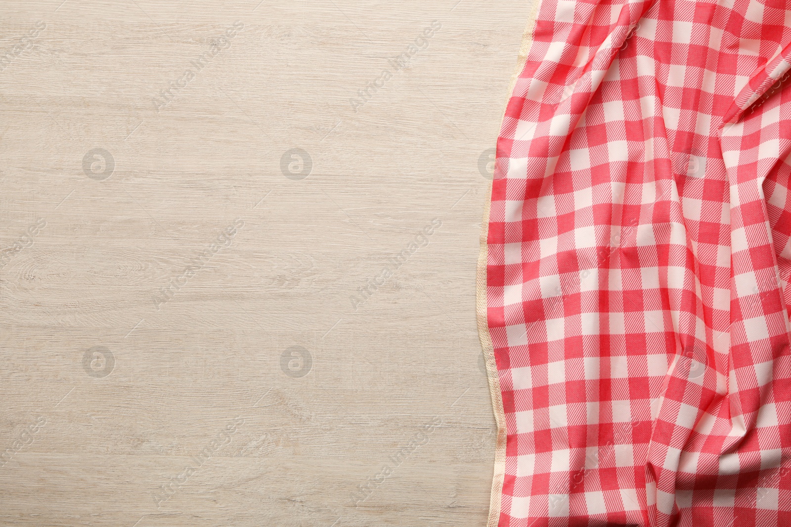 Photo of Red checkered picnic tablecloth on wooden table, top view. Space for text