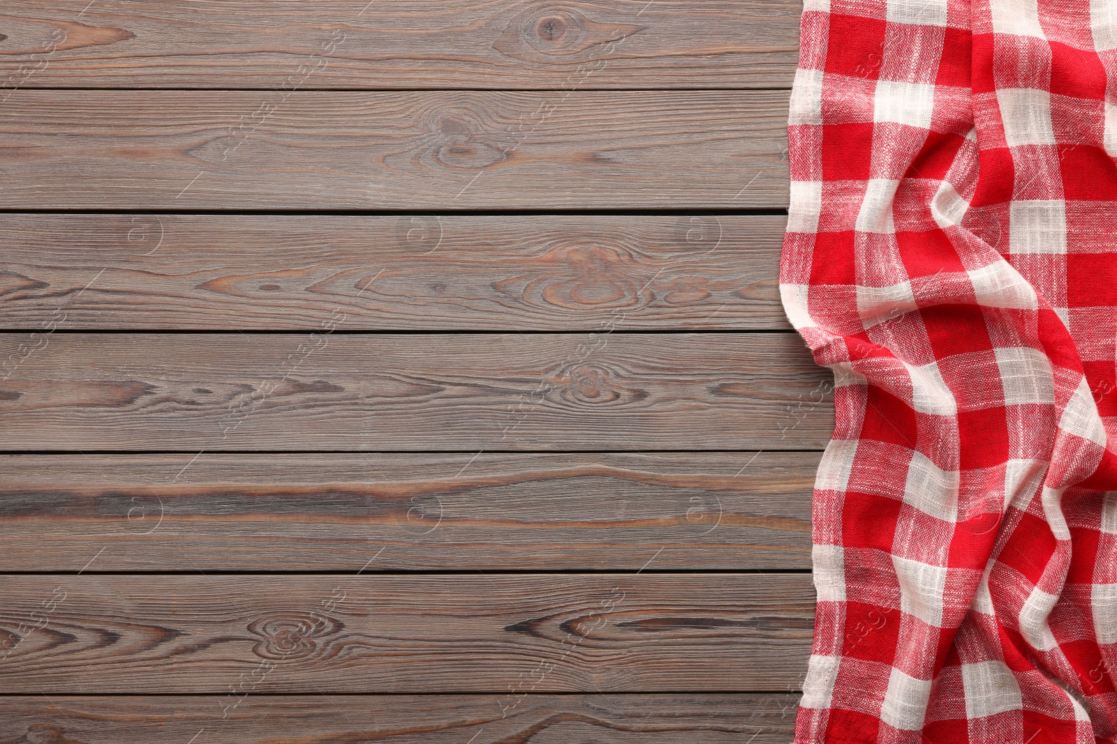 Photo of Red checkered picnic tablecloth on wooden table, top view. Space for text