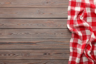 Photo of Red checkered picnic tablecloth on wooden table, top view. Space for text