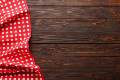 Photo of Red checkered picnic tablecloth on wooden table, top view. Space for text