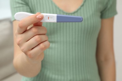 Photo of Woman holding negative pregnancy test indoors, closeup view