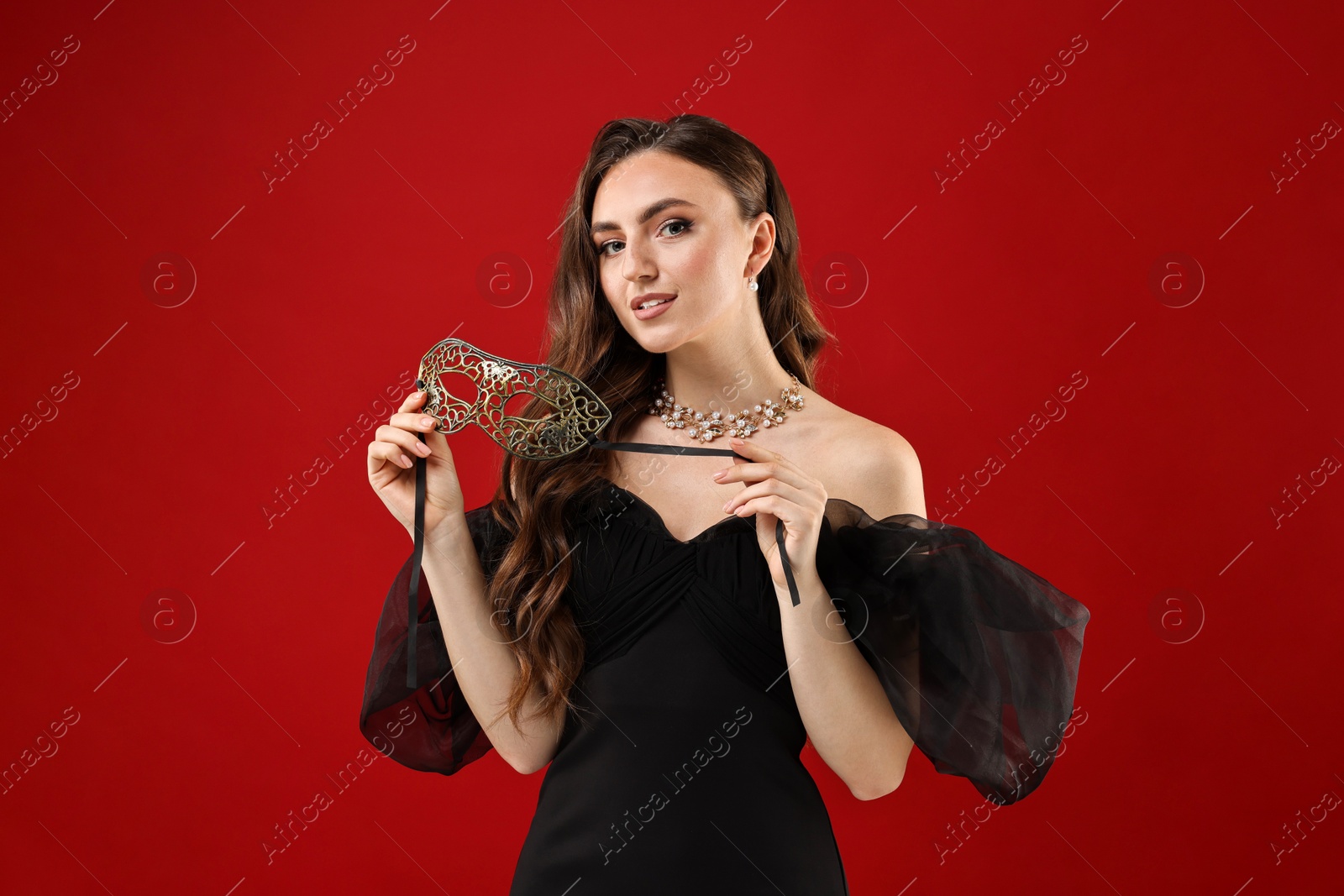 Photo of Beautiful woman with carnival mask on red background