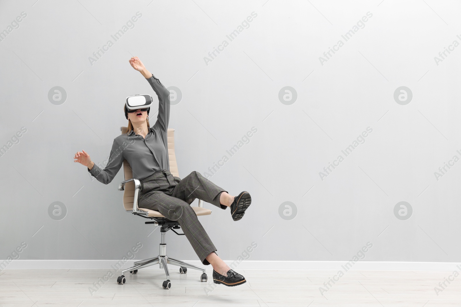 Photo of Emotional woman with virtual reality headset sitting on chair indoors, space for text