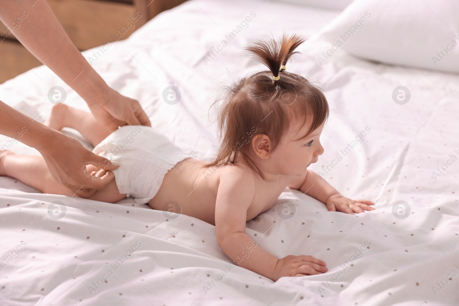 Photo of Mother changing her baby's diaper on bed, closeup