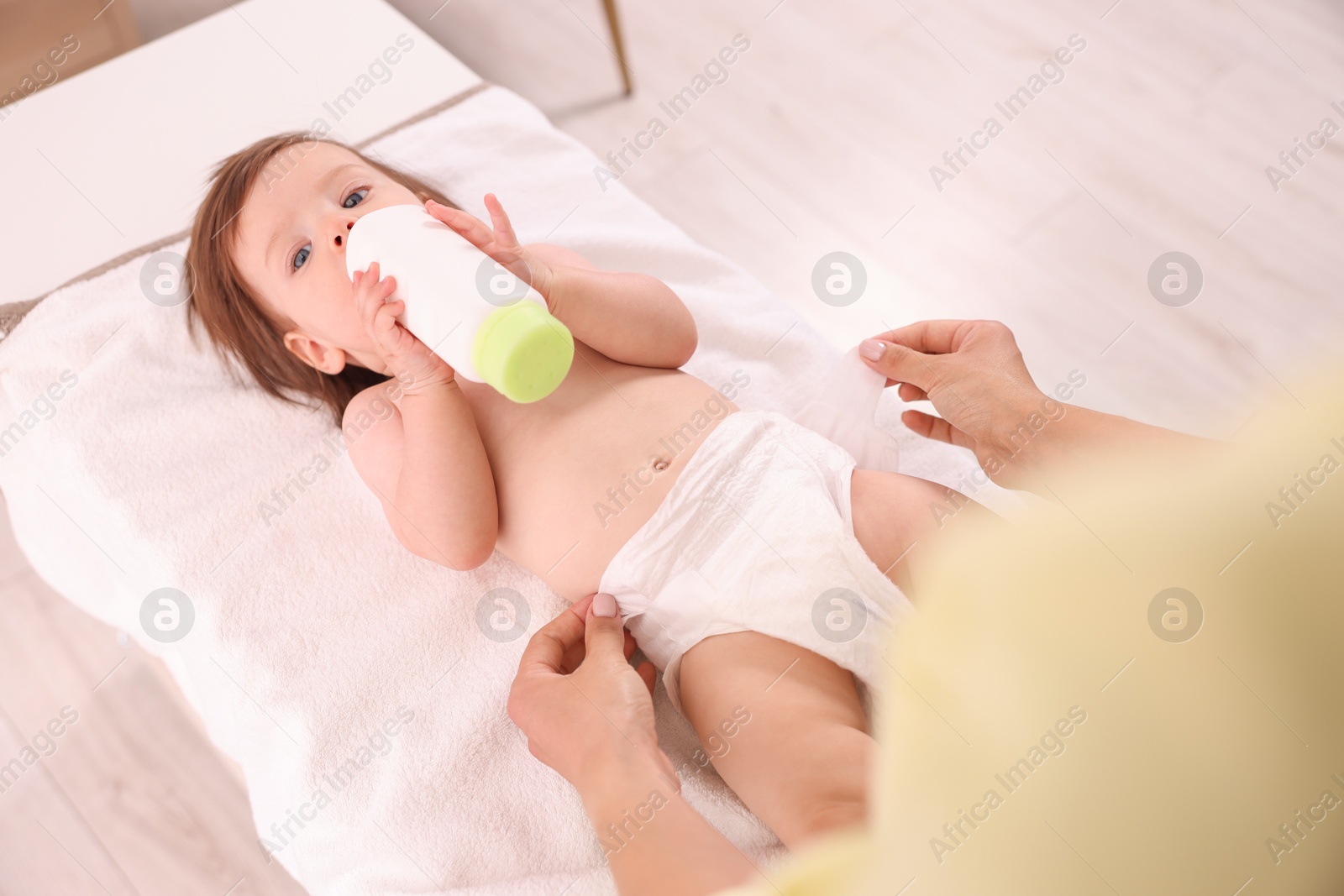 Photo of Mother changing her baby's diaper on table at home, above view