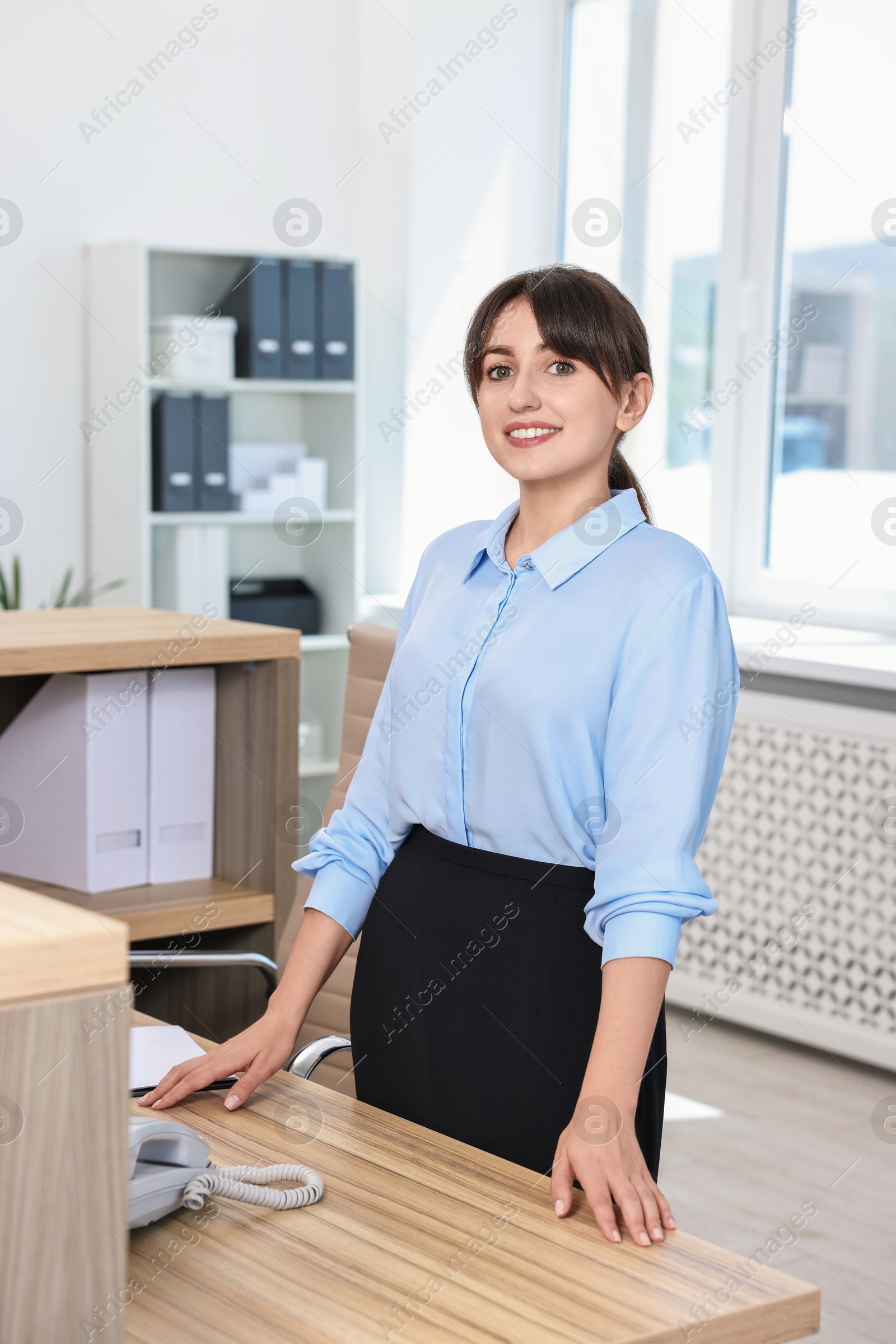 Photo of Portrait of receptionist at wooden desk in office